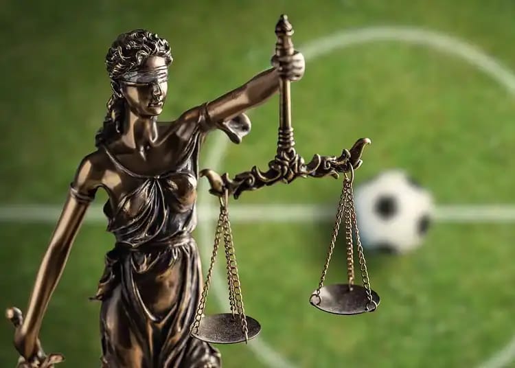 Achraf Hakimi : la justice française confirme son procès Statue de la justice avec un ballon de football en arrière-plan.