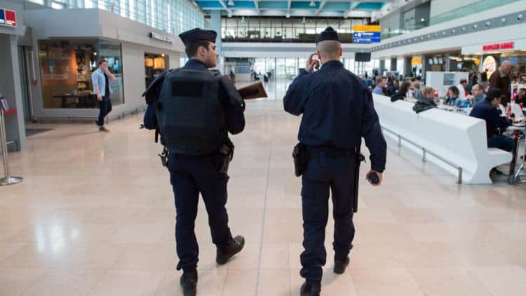 Deux policiers marchant dans un aéroport bondé en France.
