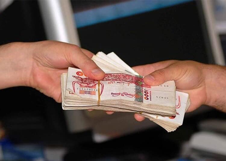 Air Algérie : billets en vente pour cette nouvelle ligne africaine Deux mains échangeant de l'argent en billets de banque algériens.