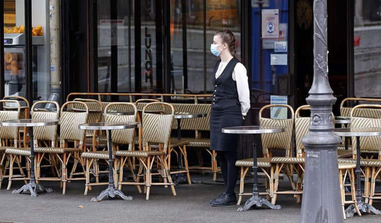 Serveuse portant un masque dans un restaurant de Lyon avec des tables vides.