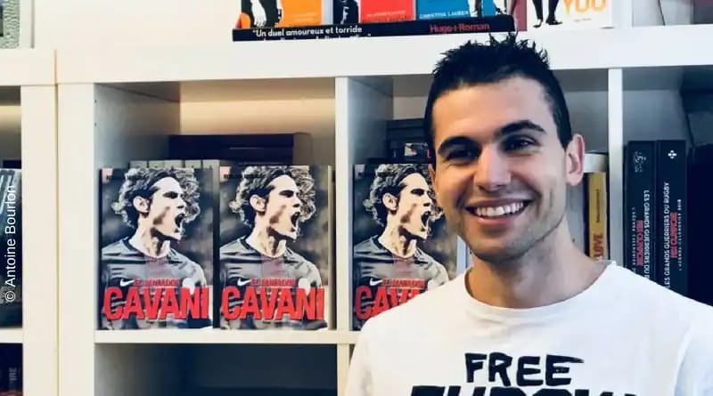Romain Molina souriant devant une bibliothèque avec des livres sur Cavani.