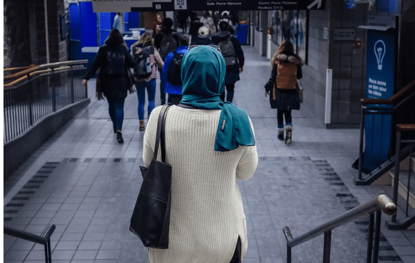 Femme portant un hijab turquoise dans une gare animée.