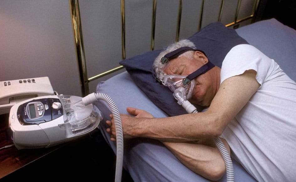 Patient âgé utilisant un masque CPAP pour troubles respiratoires.