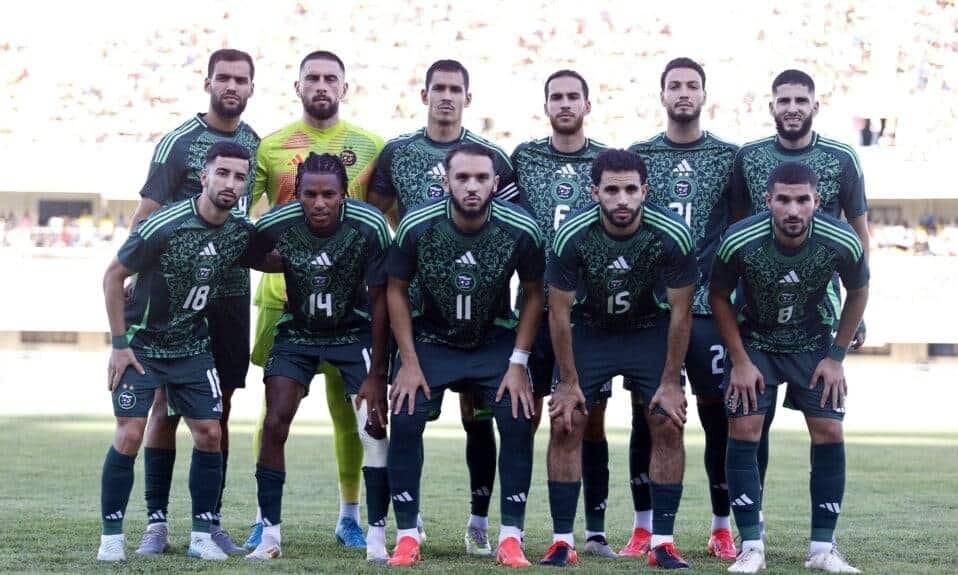 Groupe de joueurs de football algériens en tenue officielle sur le terrain.