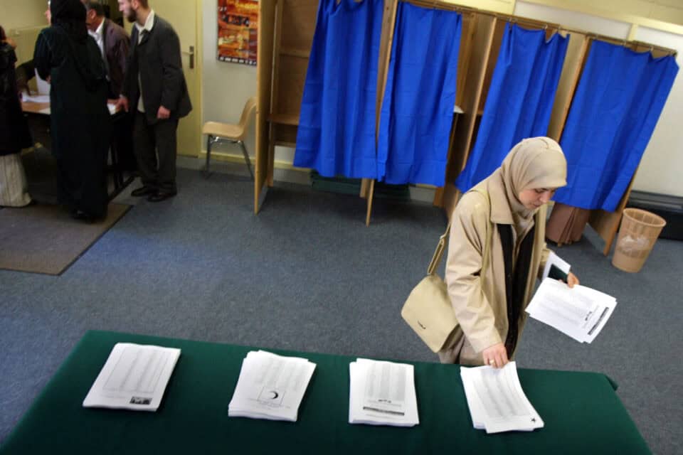 Votant féminin vérifiant des documents dans un bureau de vote.