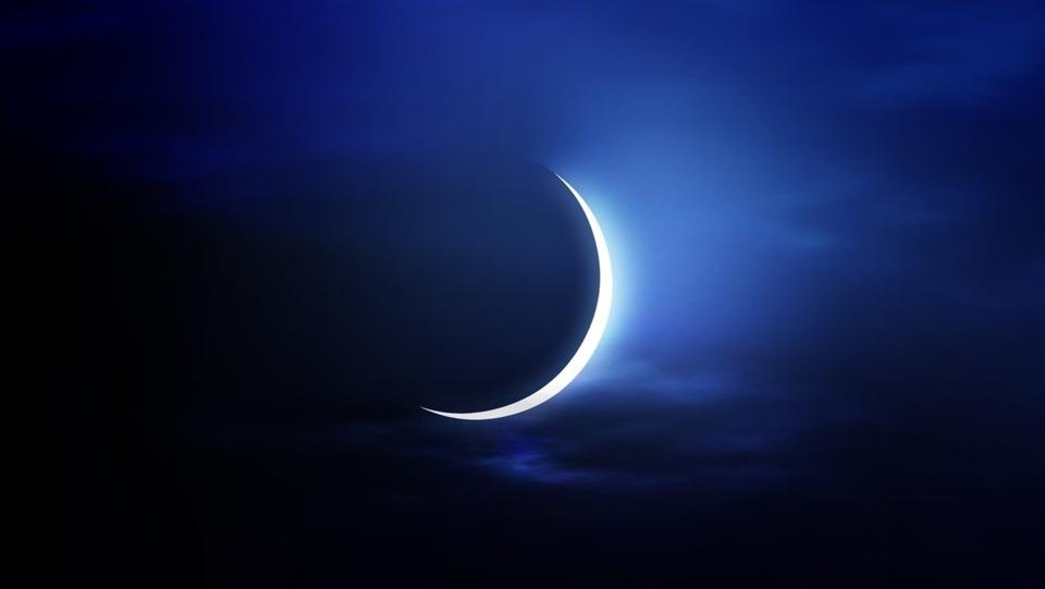 Lune croissante brillante dans un ciel nocturne avec nuages.